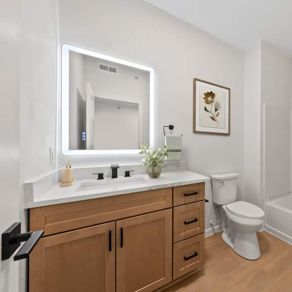 A white bathroom with a wooden vanity and a white toilet.