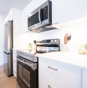 a kitchen with white cabinets and a stainless steel oven and microwave