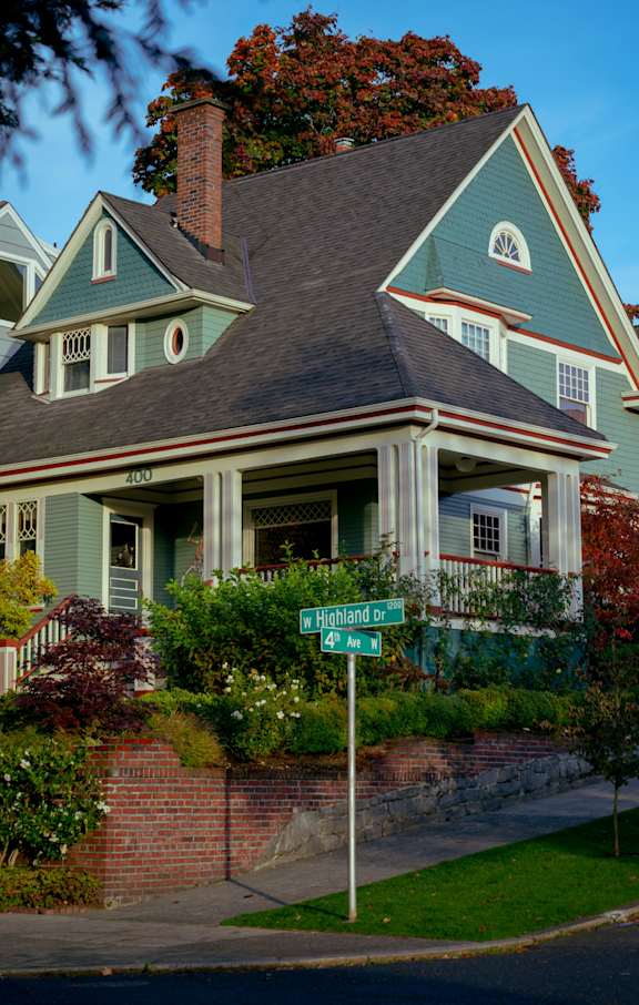 A green house with a sign in front of it.