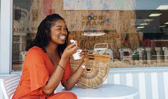 a woman sitting at a table in front of a restaurant with a cup of coffee
