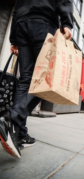 a man is walking down the sidewalk holding shopping bags