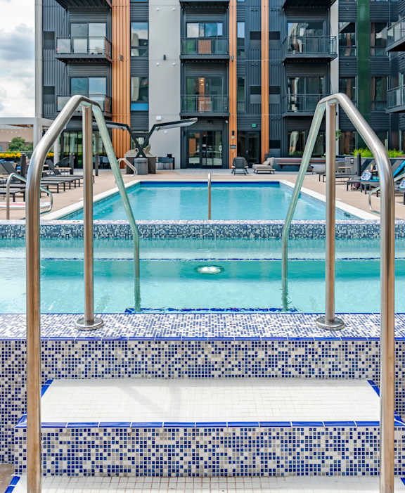 A blue and white tiled pool with a metal ladder.