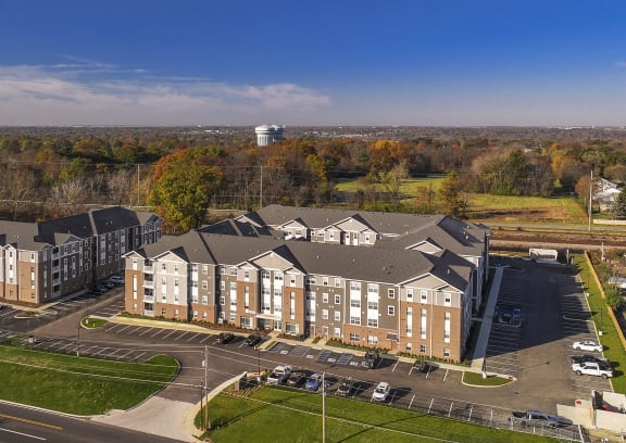 an aerial view of an apartment building with a parking lot and trees
