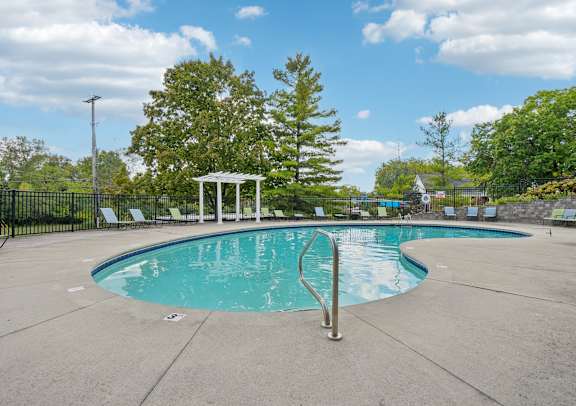 A pool with a diving board and a gazebo in the background.