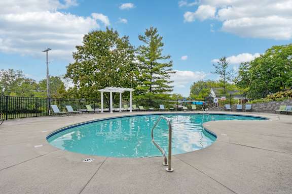 A pool with a diving board and a gazebo in the background at Glens of Bloomfield Apartments, Michigan, 48301