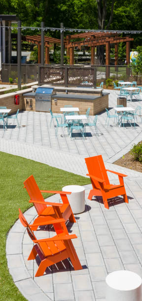an outdoor patio with orange chairs and a lawn  at Link Apartments® Canvas, Atlanta