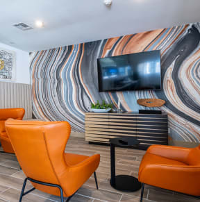 the lobby of a hotel with orange chairs and a television