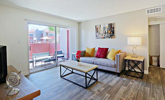 a living room with a couch and a table   and a balcony at Spring Meadow Apartments, Glendale, AZ