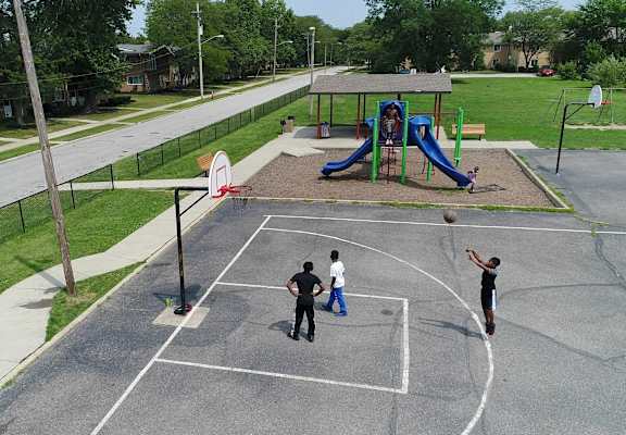 Three people playing basketball on an outdoor court.