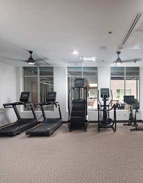 a gym with treadmills and other exercise equipment in a room with windows