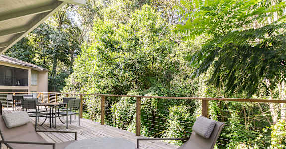 a deck with a table and chairs and trees in the background