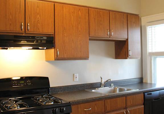 an empty kitchen with black appliances and wooden cabinets
