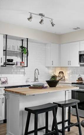 A kitchen with white cabinets and a black countertop.