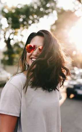 A woman with sunglasses on her head is standing outside.