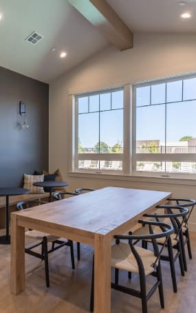 A long wooden table with chairs is in front of a window at Cascade Place Apartment Homes, Molalla, OR, 97038