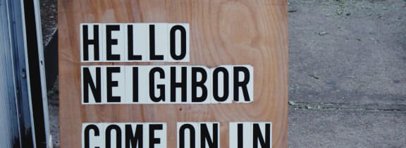 a sign that reads hello neighbor come on in on a wooden board