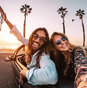 two women laughing in the back of a car on the beach
