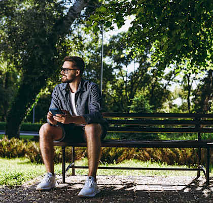 A man is sitting on a bench in a park.