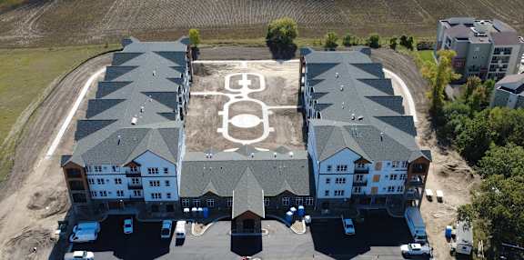 A large building with a lot of windows and a parking lot in front.