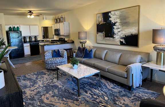 A living room with a grey couch and a painting on the wall.
