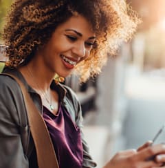 a young woman looking at her cell phone while sitting on a bench