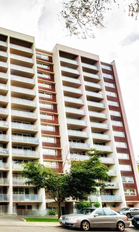 A tall apartment building with a parking lot in front.