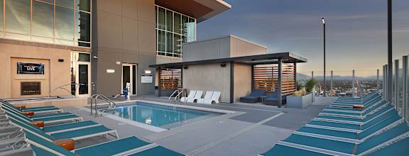 A pool area with sun loungers and a building in the background.