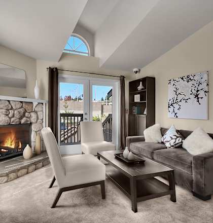 A modern living room with a stone fireplace and a skylight.