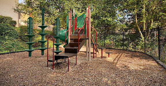 A playground with a red slide and green climbing frame.