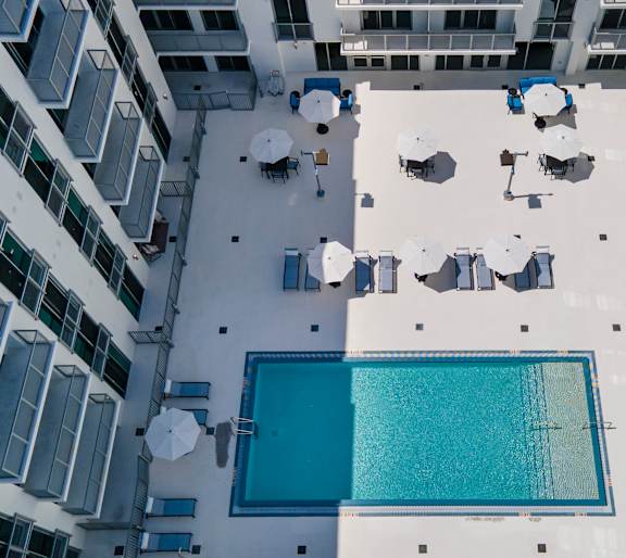 A swimming pool surrounded by white umbrellas and chairs.