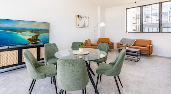 a living room with a glass table and chairs and a tv