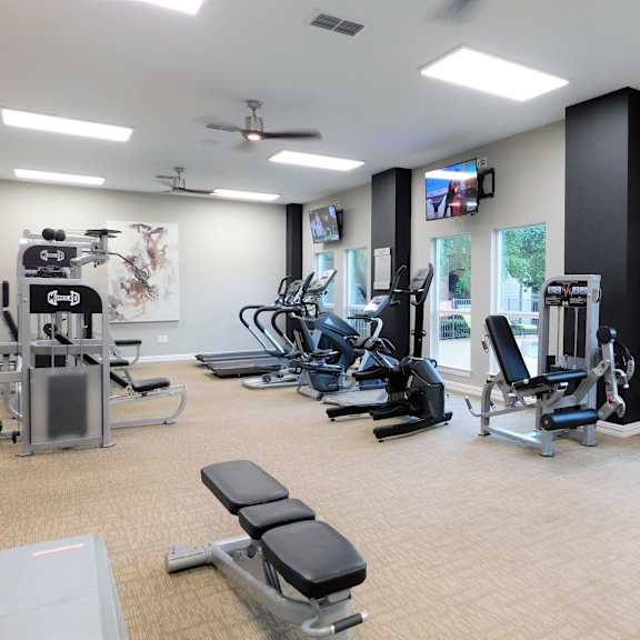 A spacious gym with a variety of equipment including treadmills, weights, and a television.