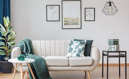 a living room with a white couch with pillows and a green blanket at The Groves, Gastonia
