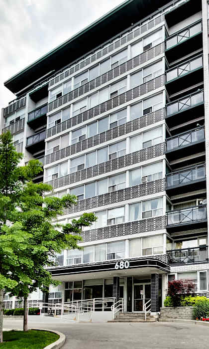 an apartment building with a driveway and trees in front of it
