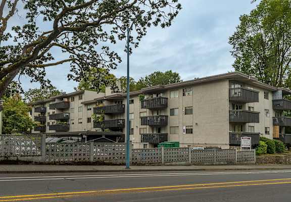 Apartment building with a fence and trees in front.