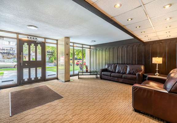 A brown leather couch sits in a room with a brown carpet.