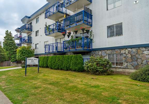 A white building with blue railings and a sign that says Lindsey Place.