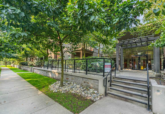 A building entrance with a metal railing and steps leading up to it.