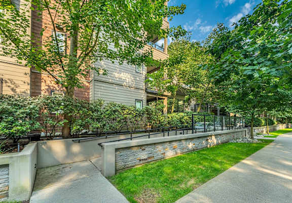 A concrete pathway leads through a grassy area in front of a building.