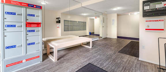 A room with a bench, a mirror, and a TV mounted on the wall.