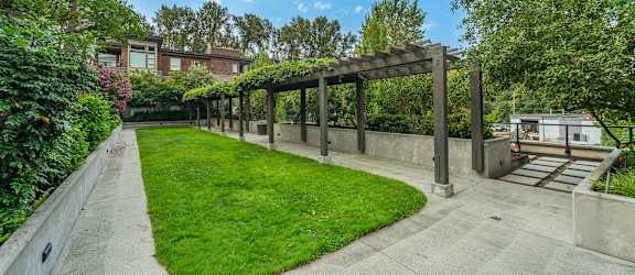 A sunny day at a park with a wooden pergola.