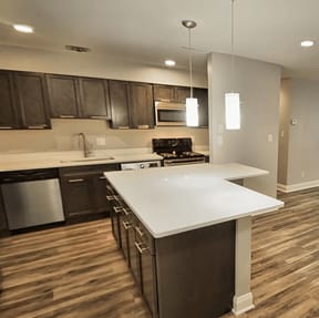 A kitchen with a white counter top and wooden floors.