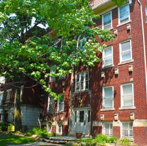 A red brick building with a tree in front.