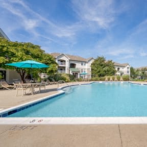a swimming pool with a blue umbrella in front of a building