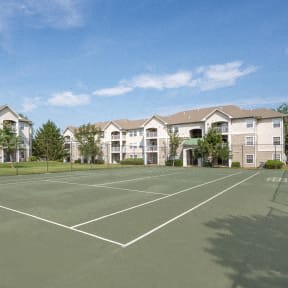 a tennis court in front of an apartment building