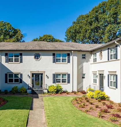 a large white building with a lawn and a sidewalk at Avondale Station Apartments in Decatur, GA