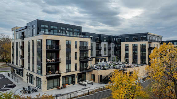 A modern multi-story building with a parking lot in front.