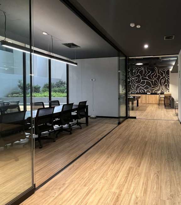 A modern office space with glass walls and wooden floors.