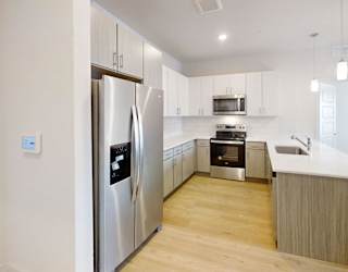 A modern kitchen with a refrigerator, microwave, oven, and sink.