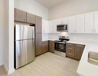 A modern kitchen with a stainless steel refrigerator and a white sink.